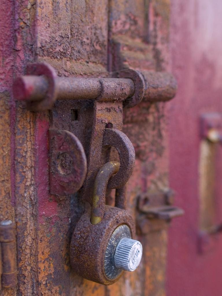 Close view of a sturdy padlock and bolt on a painted door